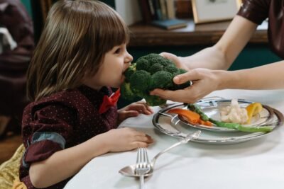 Na imagem, criança tendo alimentação rica com vegetais